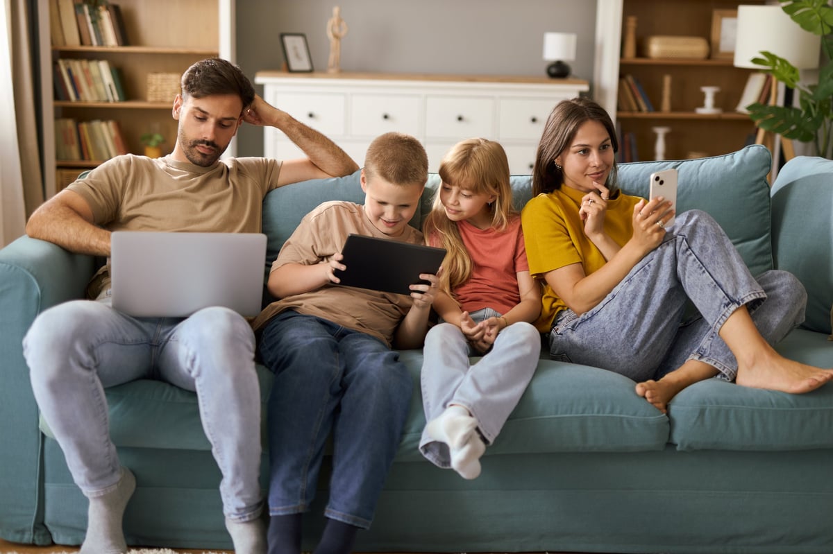 Family using wireless technology together on sofa in the living room